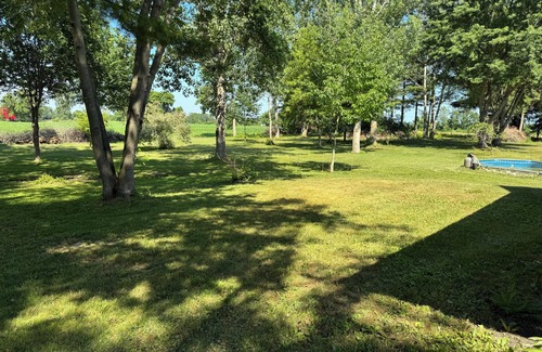 Dunnville House | Serene log home on spacious land with trees and a small farm.
