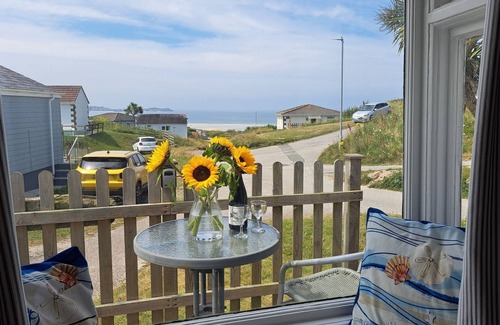 Hayle Ski Chalet | Treville soaks up the sun, which can be enjoyed from the deck with sea views.