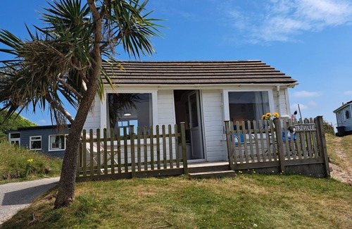 Hayle Ski Chalet | Treville soaks up the sun, which can be enjoyed from the deck with sea views.
