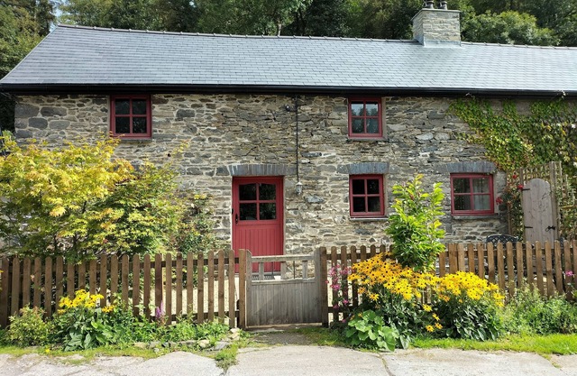 A cosy former horse stable with stone walls and old beams throughout