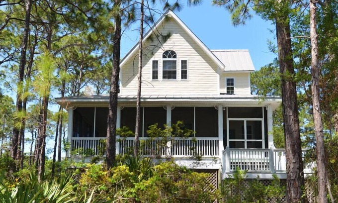 Plantation House | This sweet cottage is fenced by lush, natural landscaping and offers a peek of the Apalachicola Bay.